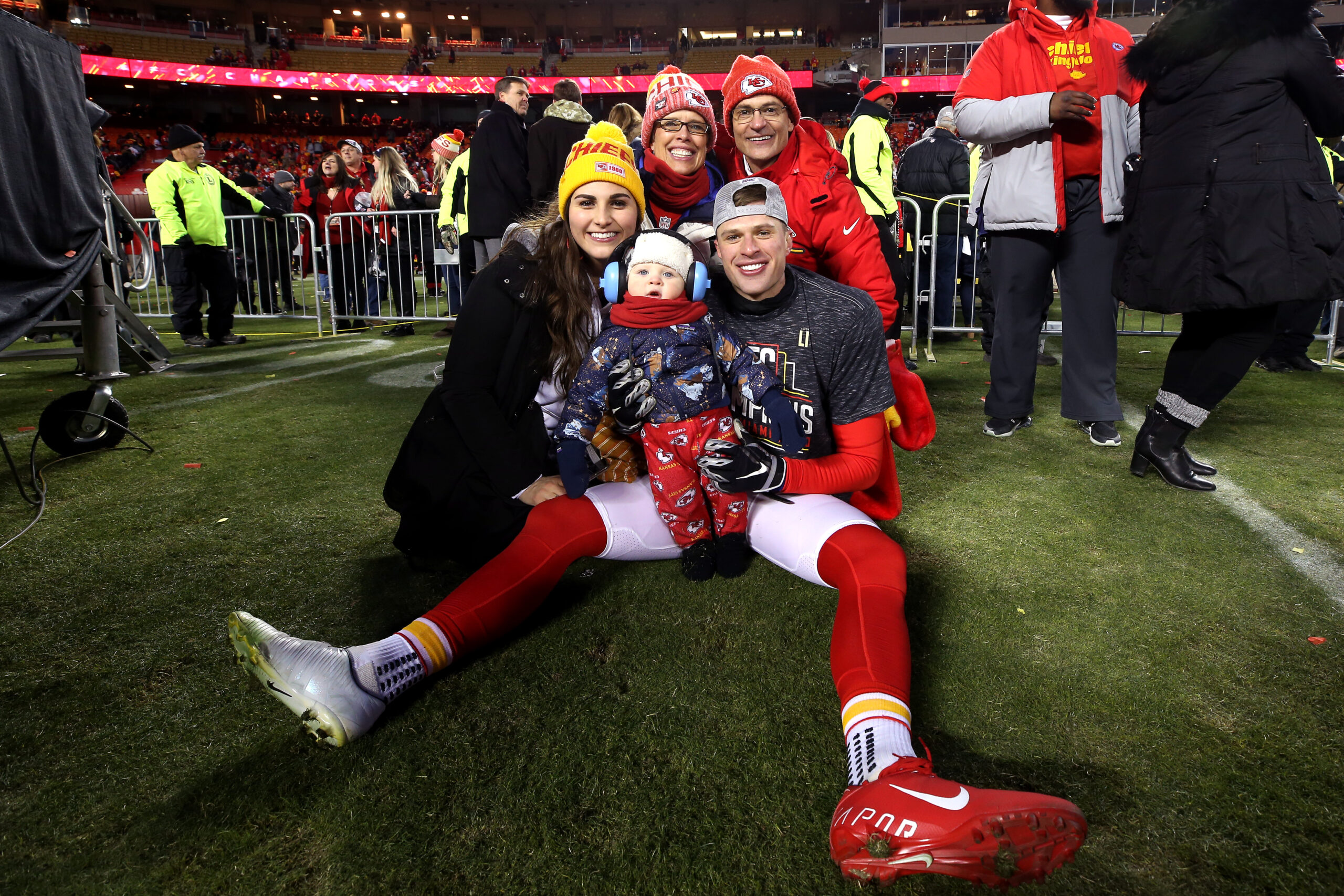 Harrison Butker and his wife, Isabelle Butker, posing on a field with family.