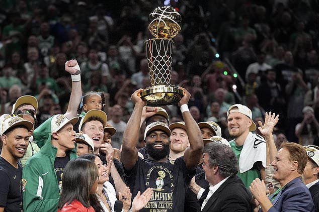 FILE - Boston Celtics guard Jaylen Brown, center, holds up the Larry O'Brien Championship Trophy as he celebrates with the team after they won the NBA basketball championship with a Game 5 victory over the Dallas Mavericks, Monday, June 17, 2024, in Boston. (AP Photo/Charles Krupa, FIle)